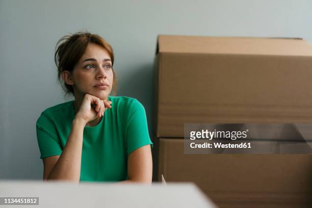 thoughtful woman next to cardboard boxes in office - 35 year old woman stock pictures, royalty-free photos & images