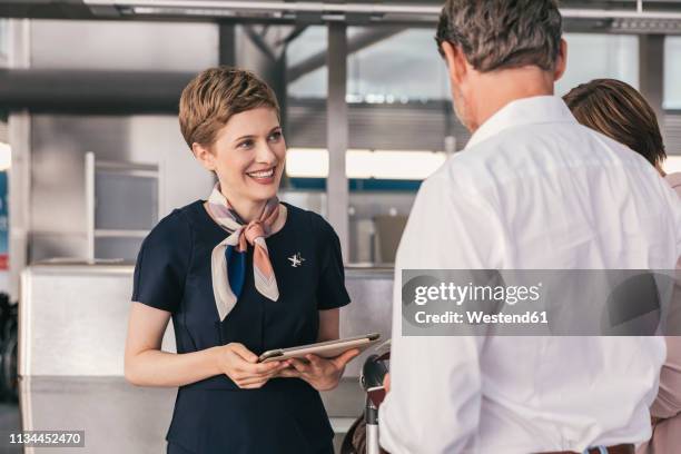 smiling airline employee talking to couple at the airport - crew foto e immagini stock