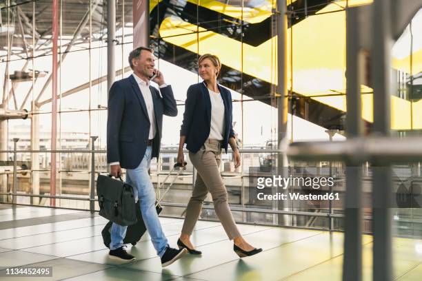 businessman on cell phone and businesswoman walking at the airport - woman airplane headphones bildbanksfoton och bilder