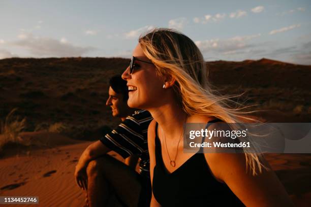 namibia, namib desert, namib-naukluft national park, sossusvlei, happy couple sitting on elim dune at sunset - couple dunes stock-fotos und bilder