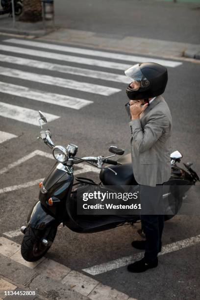 businessman next to motorscooter putting on helmet - lambreta imagens e fotografias de stock