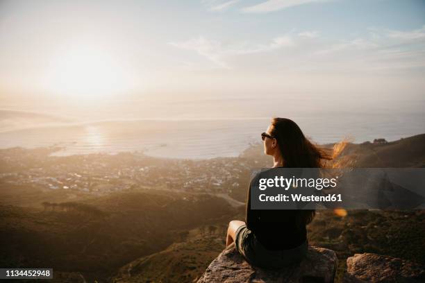 south africa, cape town, kloof nek, woman sitting on rock at sunset - beautiful south african women - fotografias e filmes do acervo