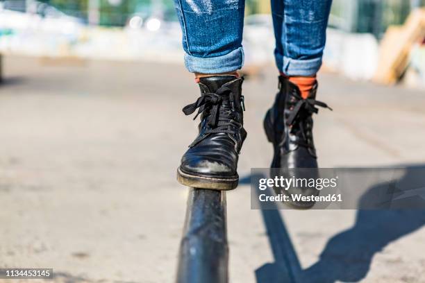 boots of a woman balancing on rail - black boot foto e immagini stock