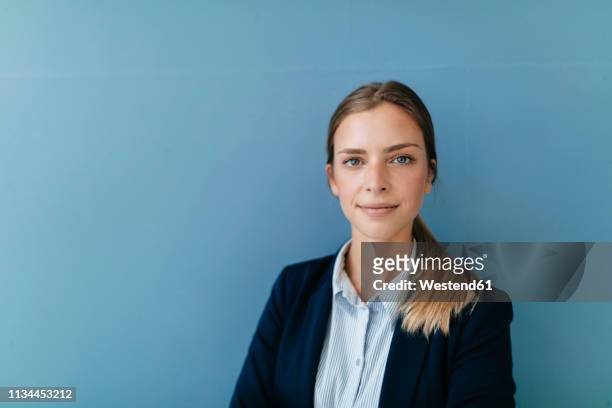 portrait of a young businesswoman against blue background - woman blue background stock pictures, royalty-free photos & images