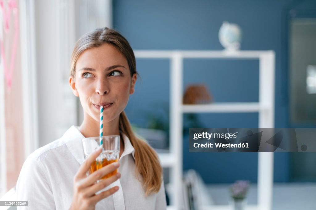 Young woman drinking tea with a straw