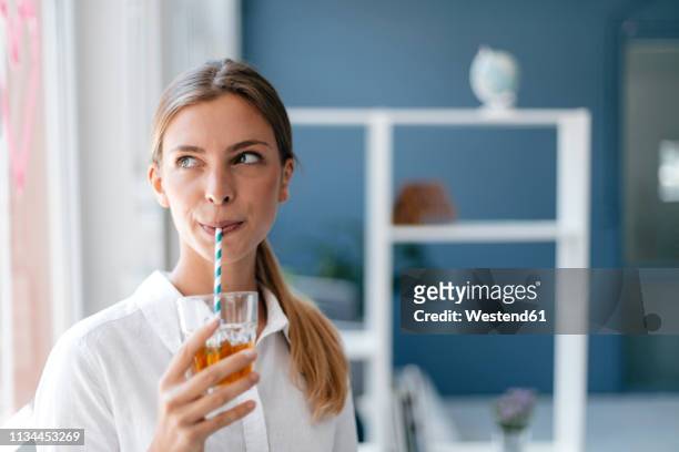 young woman drinking tea with a straw - koude dranken stockfoto's en -beelden