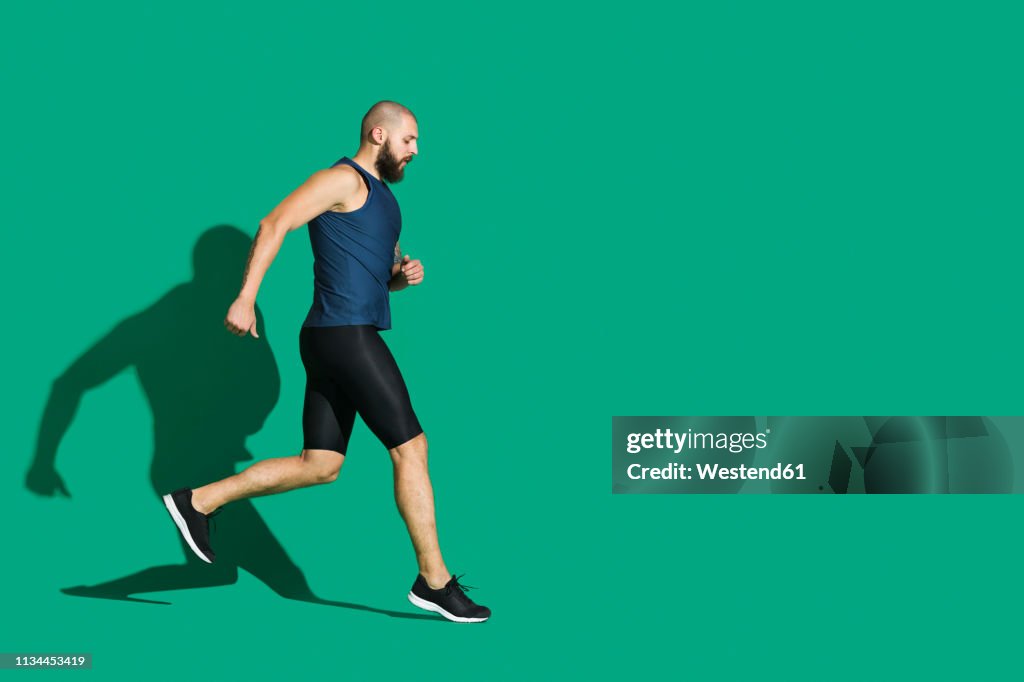 Bearded man jogging in front of green background