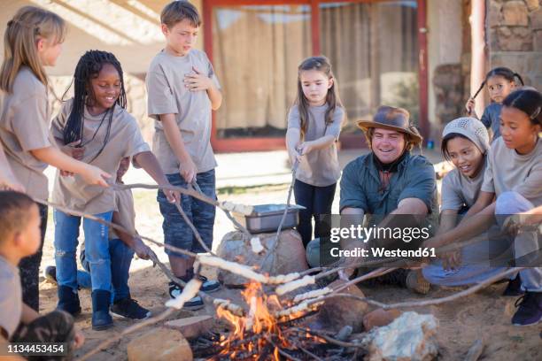 children and guide roasting twist bread at camp fire - girl scout camp stock pictures, royalty-free photos & images