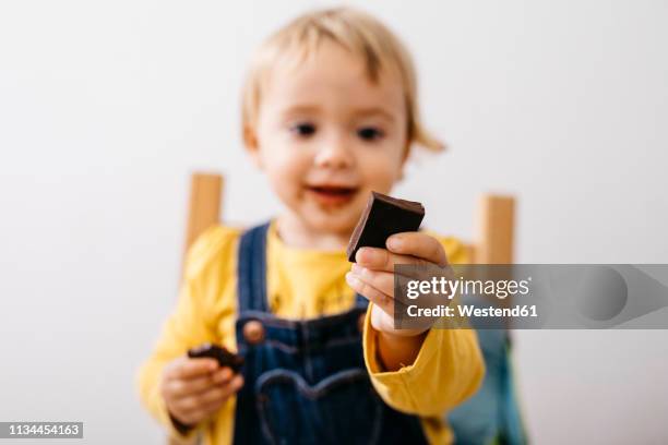 hand of smiling toddler girl holding piece of chocolate, close-up - eating dark chocolate stock pictures, royalty-free photos & images
