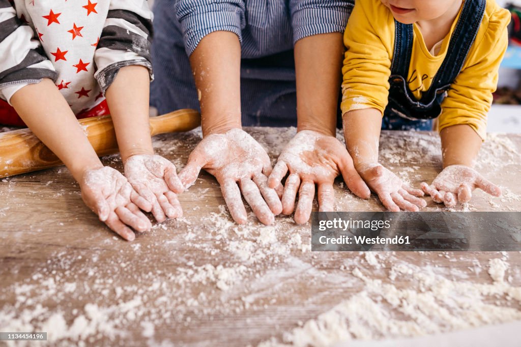 Mother and children with flour on their hands, partial view