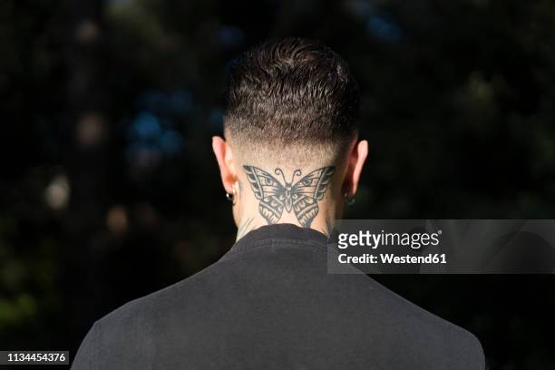 back view of man with tattooed butterfly on his neck - butterfly tattoos stock pictures, royalty-free photos & images