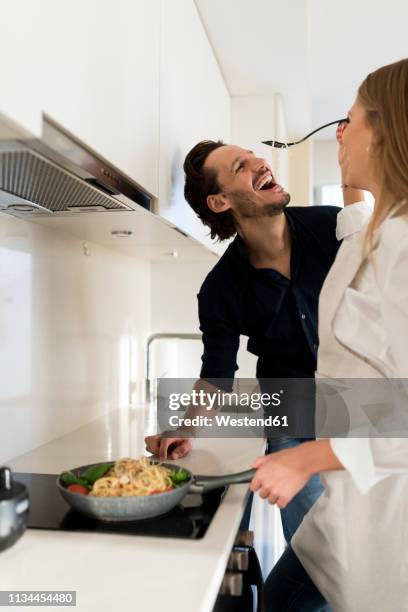 happy couple preparing spaghetti in their kitchen - the joys of eating spaghetti stock pictures, royalty-free photos & images