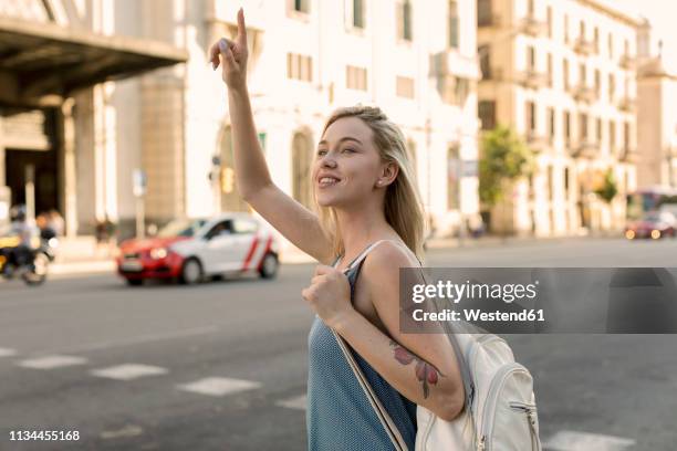 smiling young woman in the city hailing a taxi - female waving on street stock pictures, royalty-free photos & images