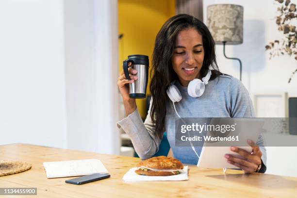 smiling woman using tablet at table - snacking on the go stock pictures, royalty-free photos & images