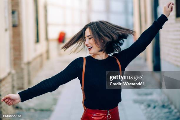 happy young woman dancing in the street - hair toss stock pictures, royalty-free photos & images