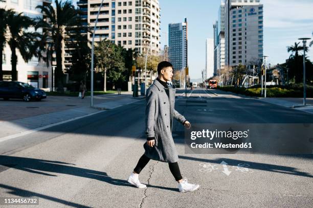 spain, barcelona, young man crossing the street - barcelona street stock-fotos und bilder