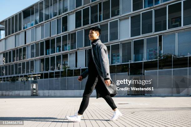 spain, barcelona, smiling young man walking down the street - person walking side view stock pictures, royalty-free photos & images