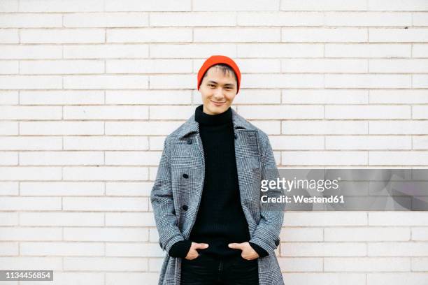 portrait of stylish young man wearing cap, black turtleneck pullover and grey coat - mens clothing stock pictures, royalty-free photos & images