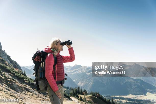 austria, tyrol, woman looking through binoculars during hiking trip - women wearing see through clothing stockfoto's en -beelden