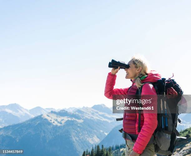 austria, tyrol, happy woman looking through binoculars during hiking trip - österreich durchblick stock-fotos und bilder