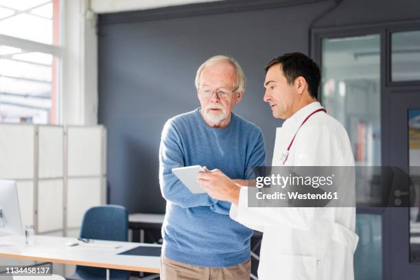doctor showing tablet to patient in medical practice - man talking to doctor bildbanksfoton och bilder