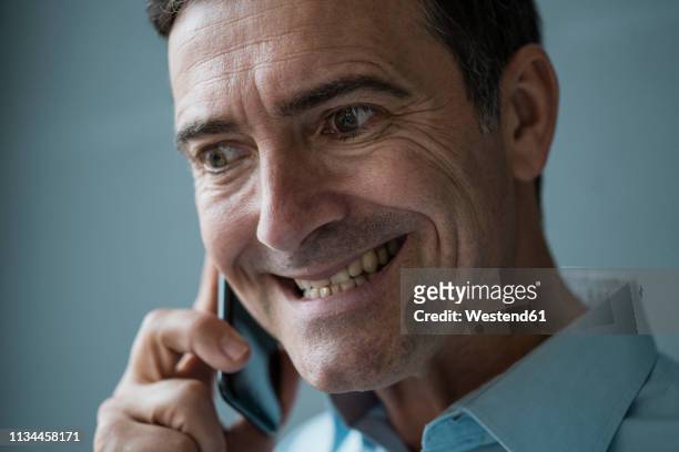 portrait of grimacing businessman on cell phone - grimacing stock pictures, royalty-free photos & images