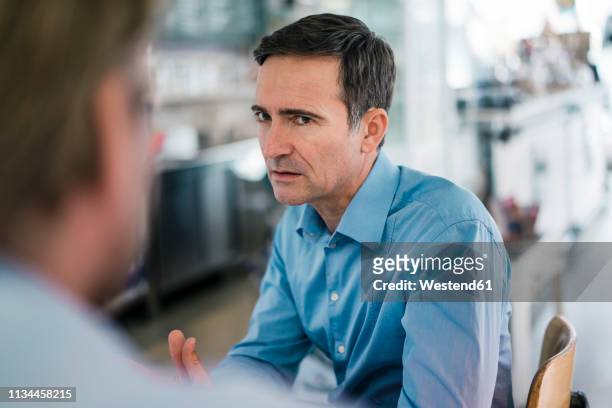 portrait of serious businessman looking at colleague - delusione foto e immagini stock