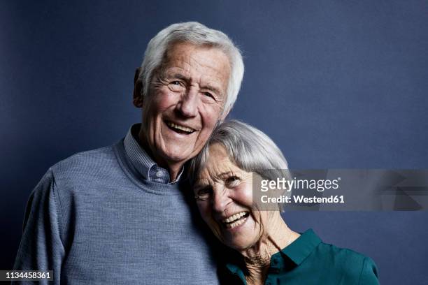 portrait of happy senior couple - portrait blue background stock-fotos und bilder