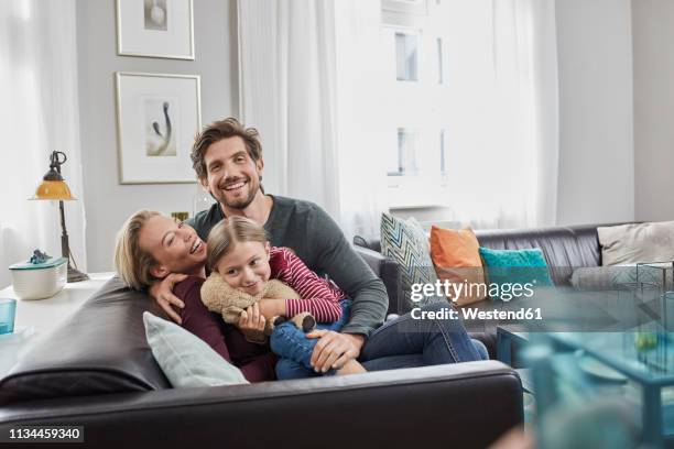 portrait of happy family sitting on couch at home - espacio confortable fotografías e imágenes de stock