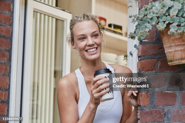 happy sporty young woman with takeaway drink at house entrance - roupa desportiva imagens e fotografias de stock