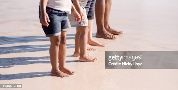 family standing barefoot at the beach - kids feet stock pictures, royalty-free photos & images