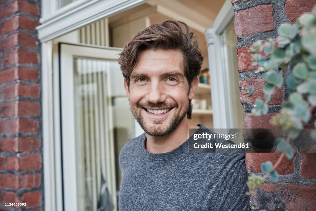 Portrait of smiling man at house entrance