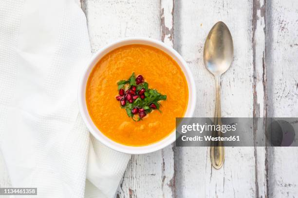 bowl of carrot ginger coconut soup with topping of parsley and pomegranate seed - scodella per zuppa foto e immagini stock