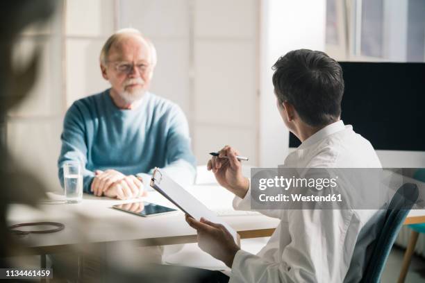 doctor talking to senior patient in medical practice - medical writer stock pictures, royalty-free photos & images