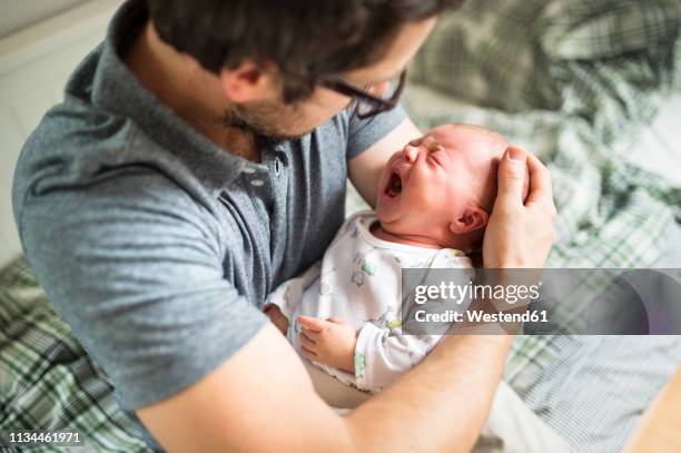 father at home consoling his crying baby daughter - babys crying stock-fotos und bilder