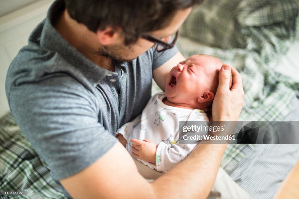 Father at home consoling his crying baby daughter