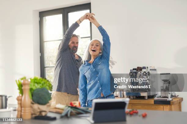 youthful senior couple dancing in the kitchen - couple dancing at home stockfoto's en -beelden