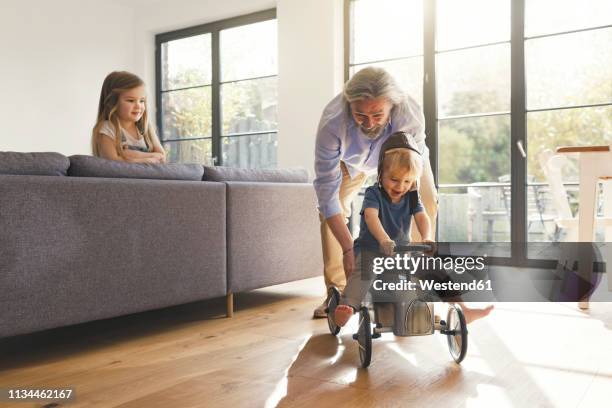 grandfather playing with grandchildren, sitting on toy car - car young and old person stock pictures, royalty-free photos & images