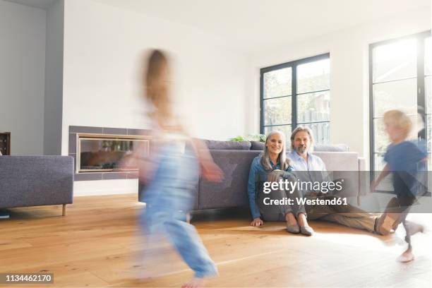 grandparents observing grandchildren, playing in livingroom - blurred motion foto e immagini stock