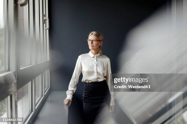 businesswoman in office looking out of window - wegsehen stock-fotos und bilder