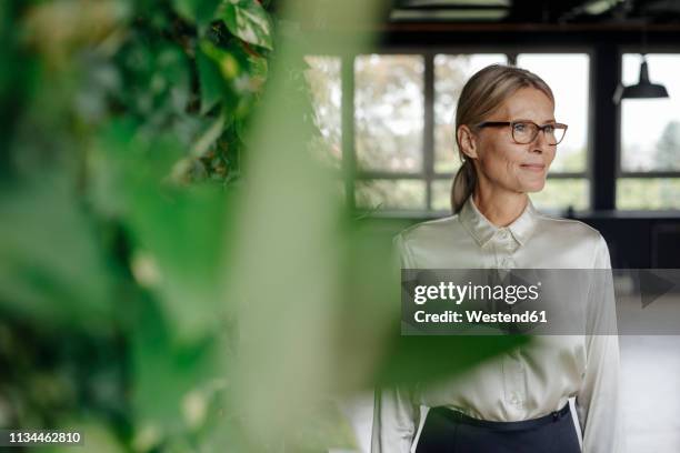 smiling businesswoman in green office - environmental conservation stock-fotos und bilder