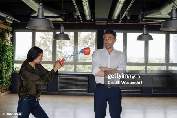 businesswoman in office hitting businessman with boxing toy - funny boxing stock-fotos und bilder