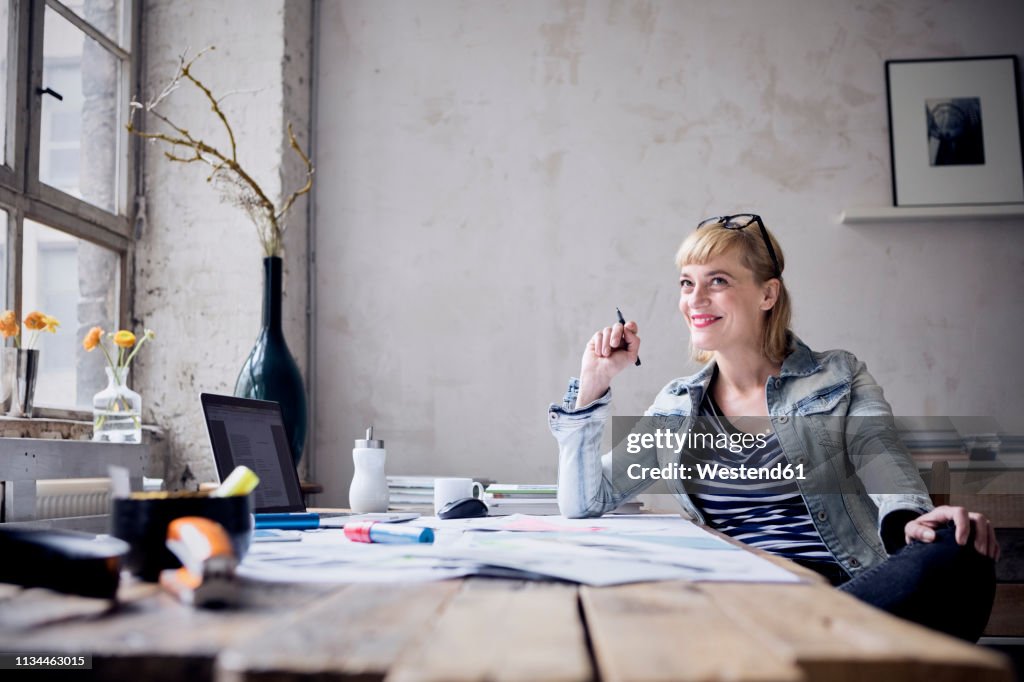 Portrait of laughing woman sitting at desk in a loft