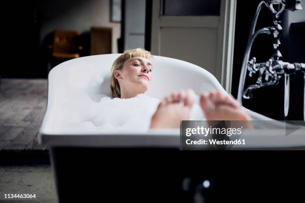 blond woman taking bubble bath in a loft - taking a bath fotografías e imágenes de stock