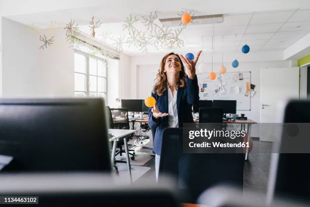 happy businesswoman juggling balls in office - fare il giocoliere foto e immagini stock