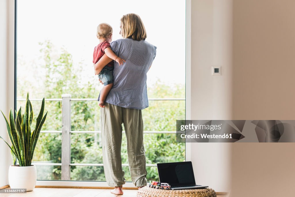 Mother carrying son, looking out of window