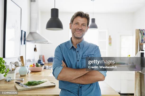 mature man at home, looking confidet - arme verschränkt mann stock-fotos und bilder