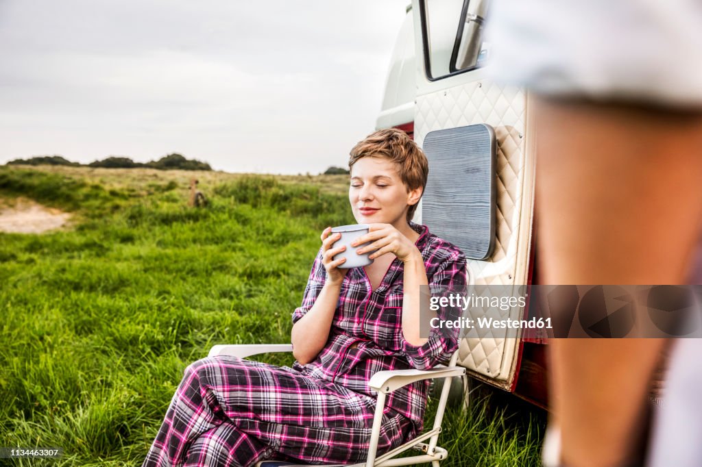 Woman in pyjama enjoying coffee at a van in rural landscape