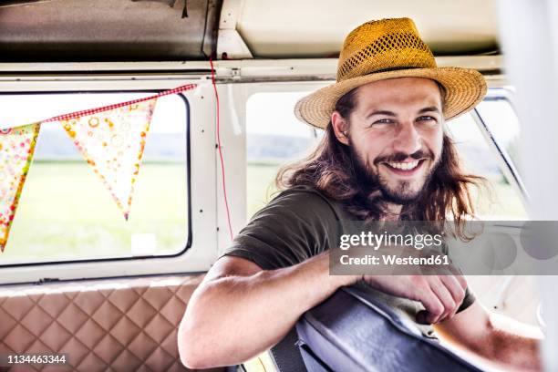 portrait of happy young man inside a van - langes haar stock-fotos und bilder