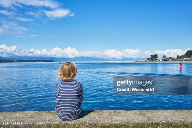 chile, puerto montt, boy sitting on quay wall at the harbor - puerto montt 個照片及圖片檔